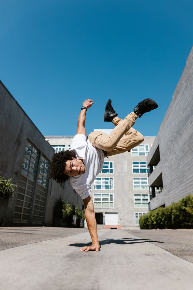 Dynamic shot of a young man breakdancing with a handstand outdoors.